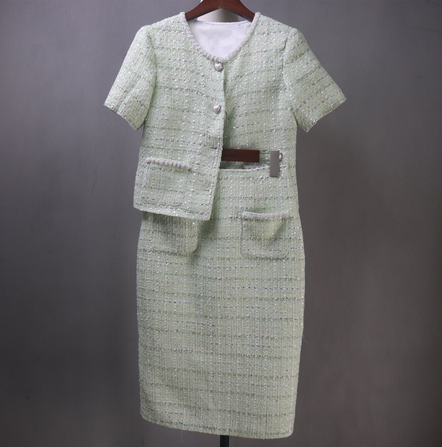 Step into timeless elegance with our bespoke light green tweed skirt suit, adorned with delicate pearl detailing. Designed to turn heads at every occasion, this stunning two-piece features a short-sleeve cropped jacket and a graceful long skirt, creating the perfect balance of classic charm and modern chic.