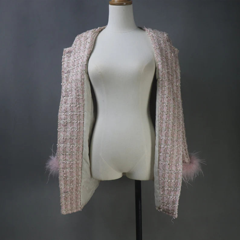 With our custom-made Faux Fur Cuffs Tweed Long Coat in a delicate shade of light pink, you may indulge in classic elegance that is ideal for your most important events. This gorgeous coat is expertly made to add to the allure of formal events, graduations, and wedding ceremonies. The opulent imitation fur cuffs lend an air of refinement, which makes it the perfect option for an evening coat that exudes elegance and grace.