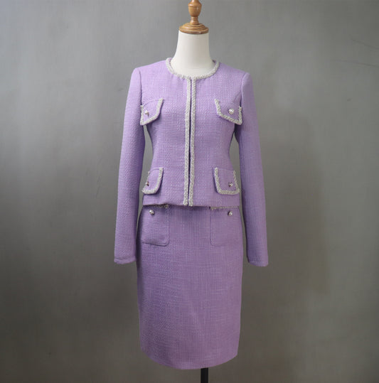 Custom-made lilac purple tweed midi skirt suit with pearl trim and decorative buttons, featuring a fitted long-sleeve blazer with four front pockets and a high-waisted pencil skirt, displayed on a mannequin against a gray background.