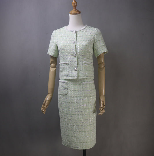 Step into timeless elegance with our bespoke light green tweed skirt suit, adorned with delicate pearl detailing. Designed to turn heads at every occasion, this stunning two-piece features a short-sleeve cropped jacket and a graceful long skirt, creating the perfect balance of classic charm and modern chic.