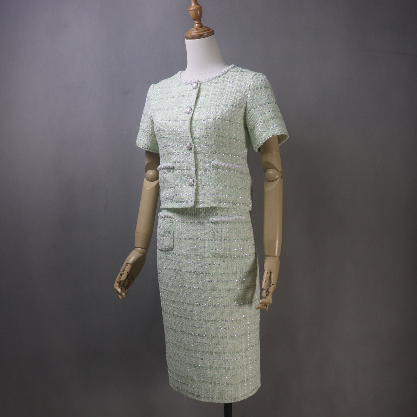 Step into timeless elegance with our bespoke light green tweed skirt suit, adorned with delicate pearl detailing. Designed to turn heads at every occasion, this stunning two-piece features a short-sleeve cropped jacket and a graceful long skirt, creating the perfect balance of classic charm and modern chic.