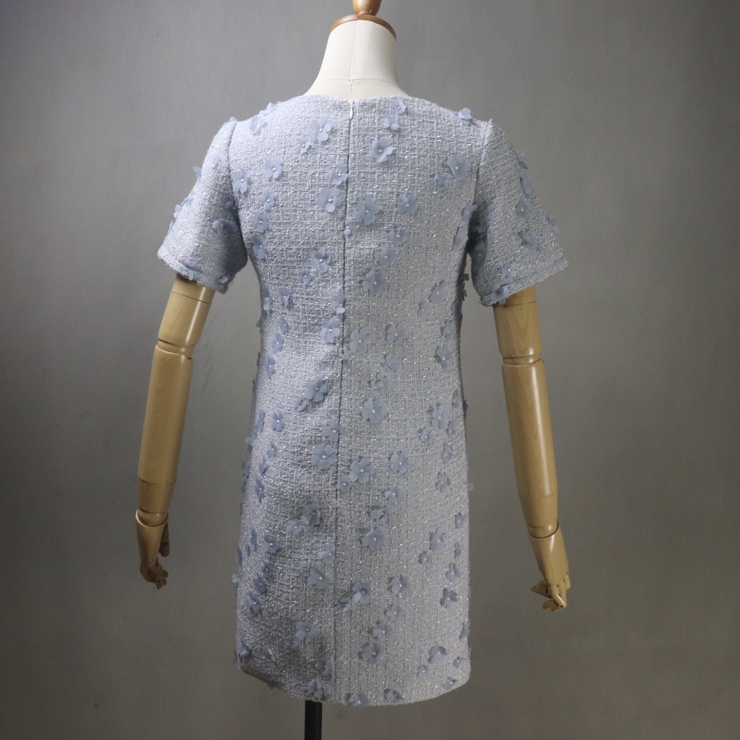 Light blue textured dress on a mannequin against a gray background