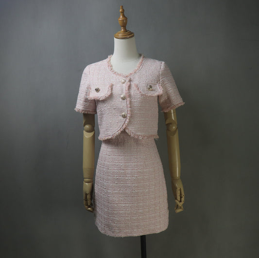 Front view of a custom handmade pink tweed two-piece outfit featuring a sleeveless mini dress and a cropped short-sleeve jacket with gold buttons and front flap pockets, displayed on a mannequin.