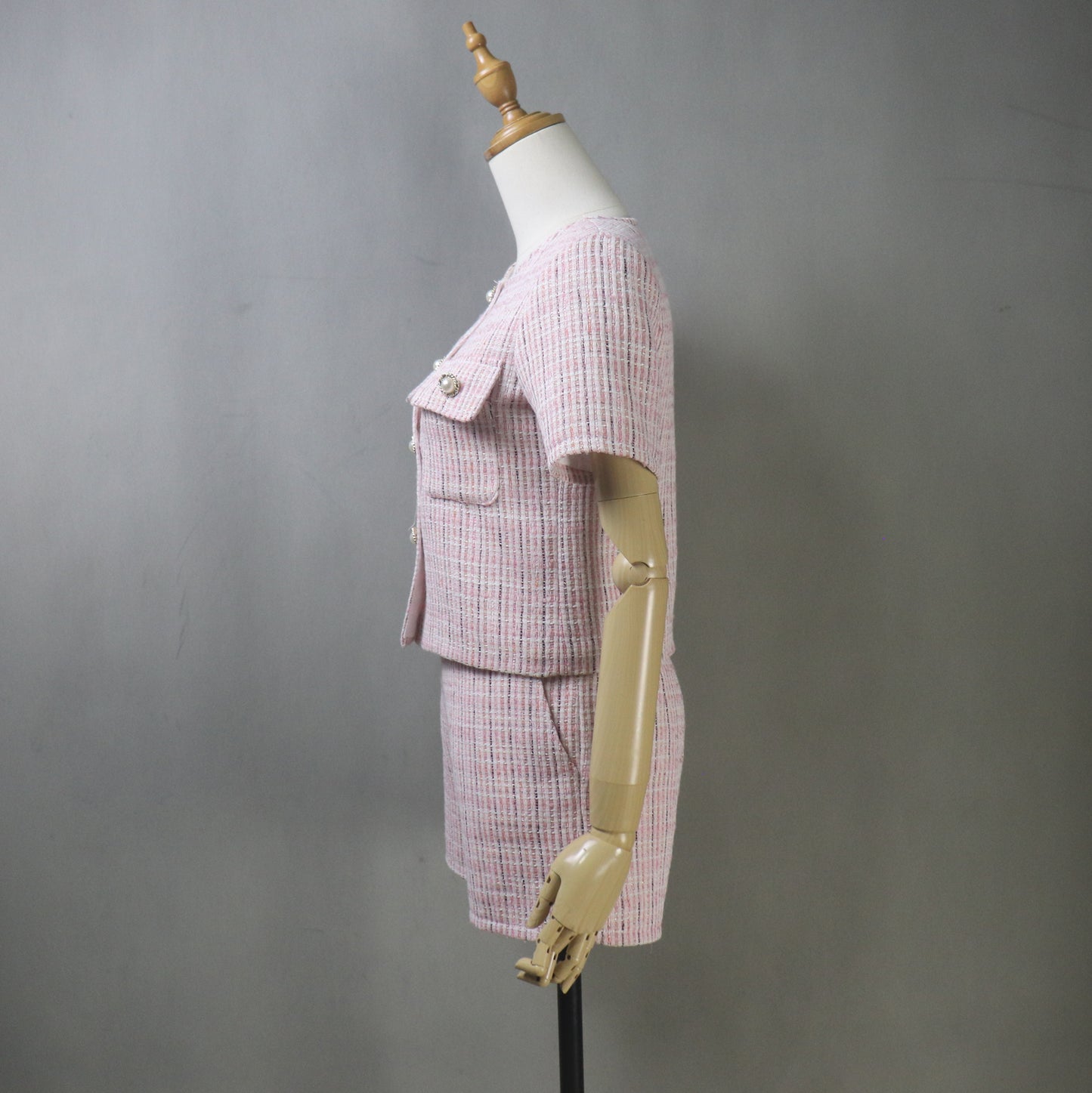 Side view of mannequin in pink tweed summer suit, showcasing the short-sleeved blazer’s tailored fit and the high-waisted shorts’ flattering silhouette