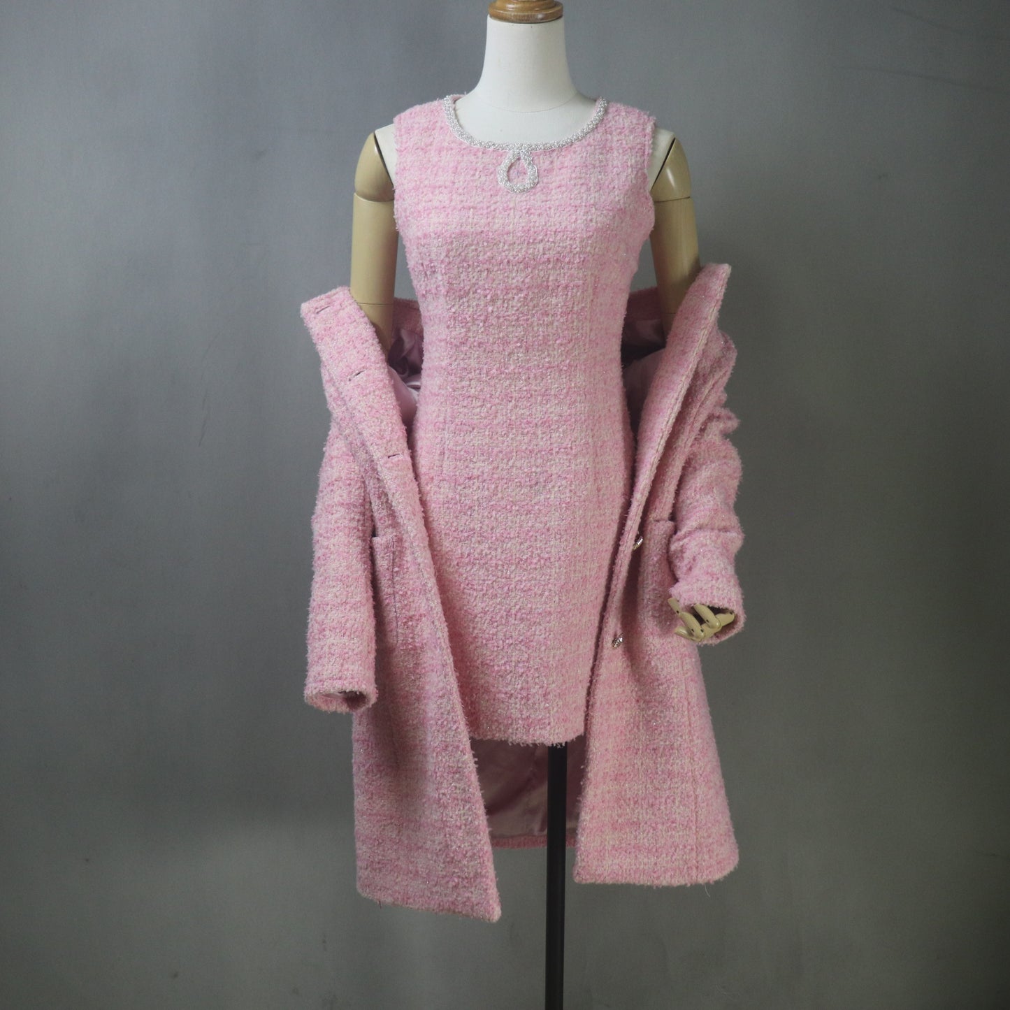 Custom-made pink boucle tweed dress suit set, featuring a fitted, mini-length sheath dress with a beaded neckline and a matching, collarless, long-line coat/jacket with front pockets and silver buttons.