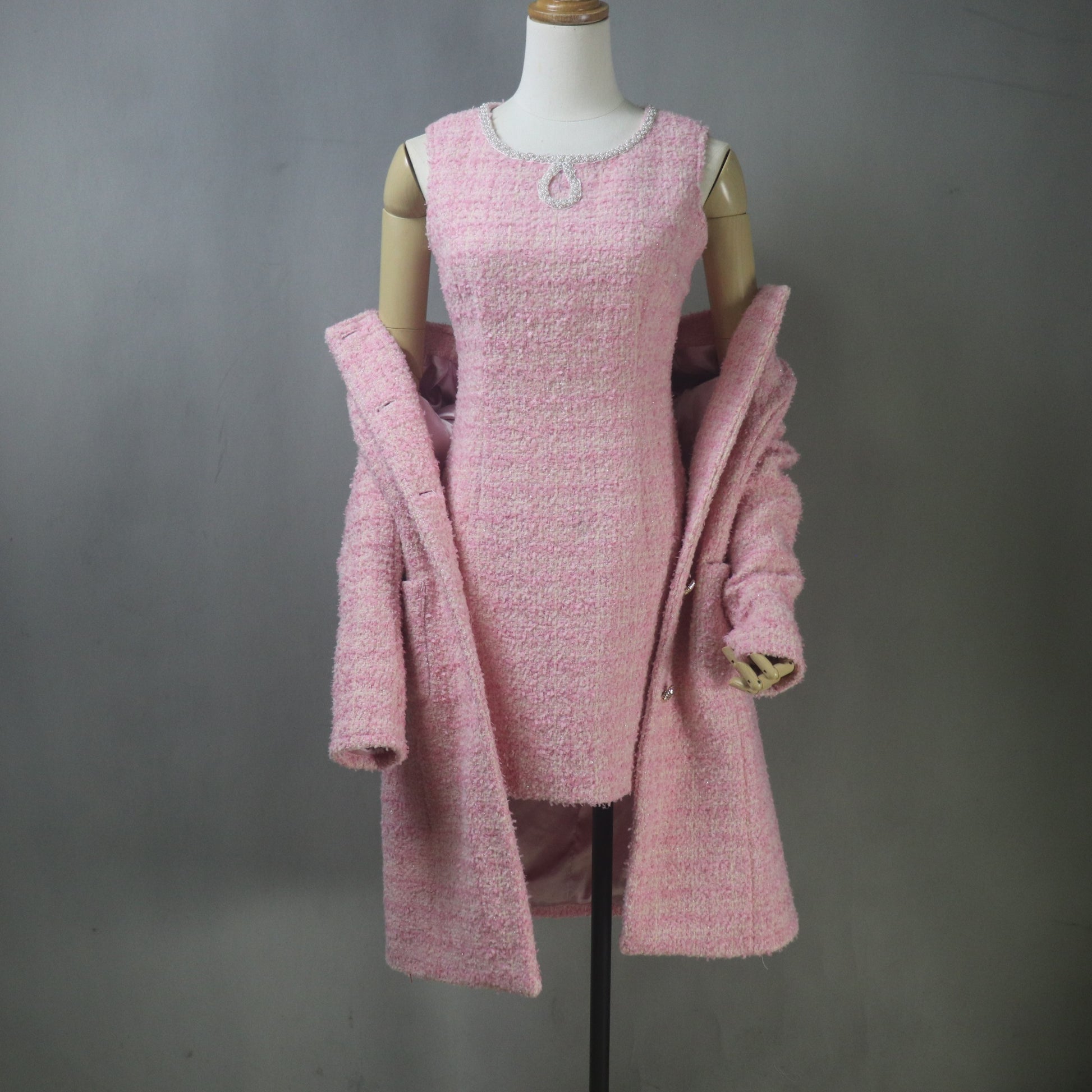Custom-made pink boucle tweed dress suit set, featuring a fitted, mini-length sheath dress with a beaded neckline and a matching, collarless, long-line coat/jacket with front pockets and silver buttons.