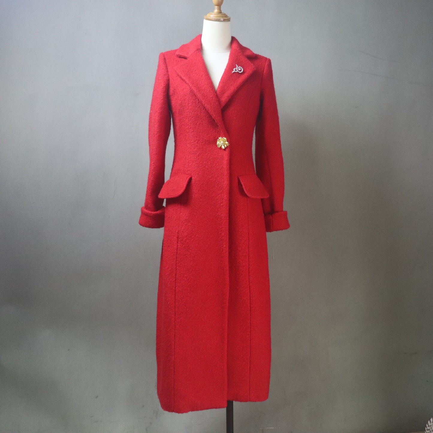 High-quality, custom-made, tailored long red wool winter coat, designed for a perfect fit and luxurious warmth. This bespoke piece features a classic single-breasted silhouette, wide notched lapels, and high-quality fabrication, styled here for a festive European winter look. The coat's striking color and precise construction emphasize the artistry of custom garment creation, ideal for clients seeking personalized, high-fashion cold-weather outerwear and unique apparel.