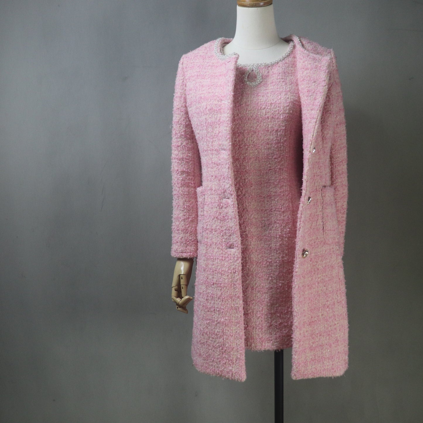 Custom-made pink boucle tweed dress suit set, featuring a fitted, mini-length sheath dress with a beaded neckline and a matching, collarless, long-line coat/jacket with front pockets and silver buttons.