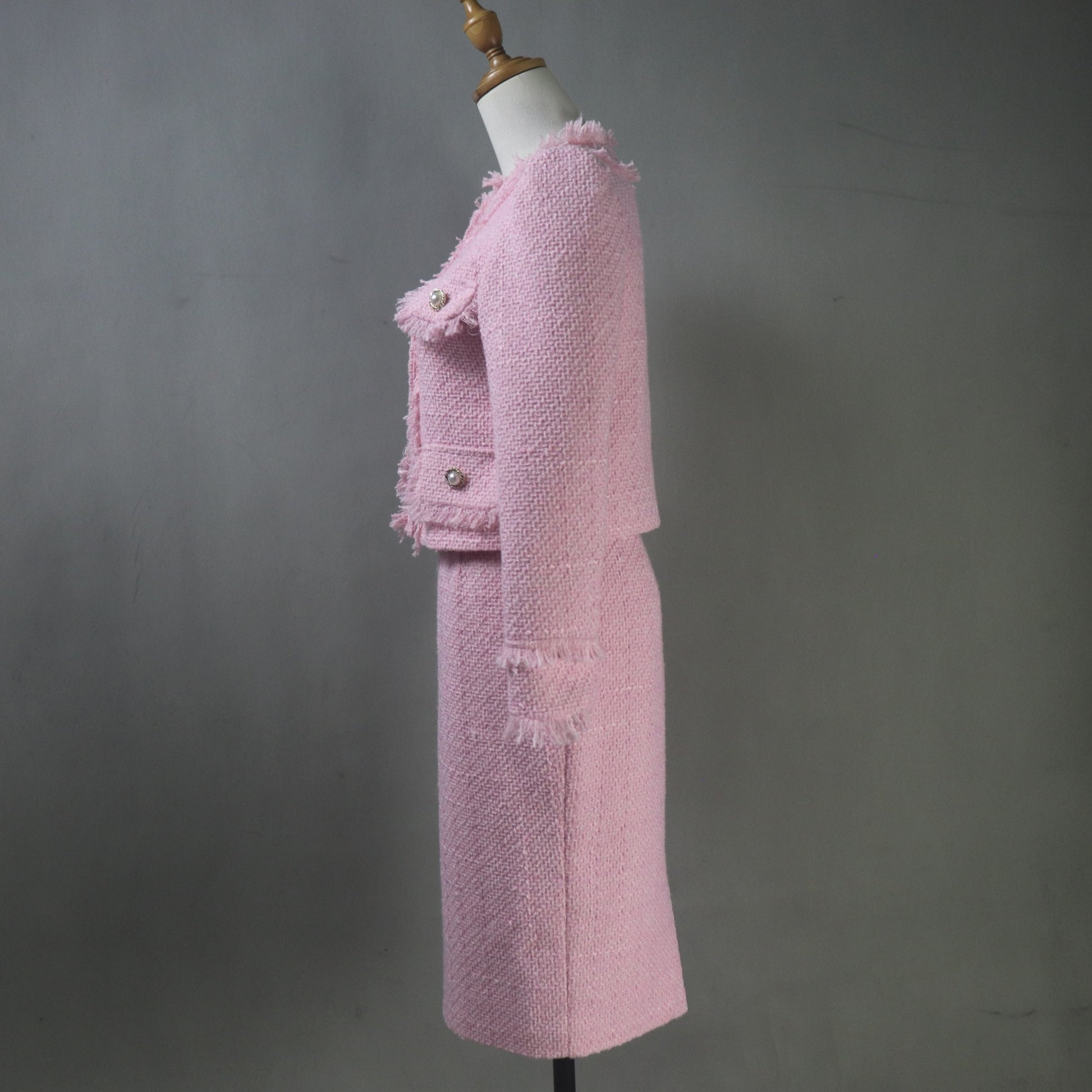 Pink tweed suit on a mannequin against a gray background