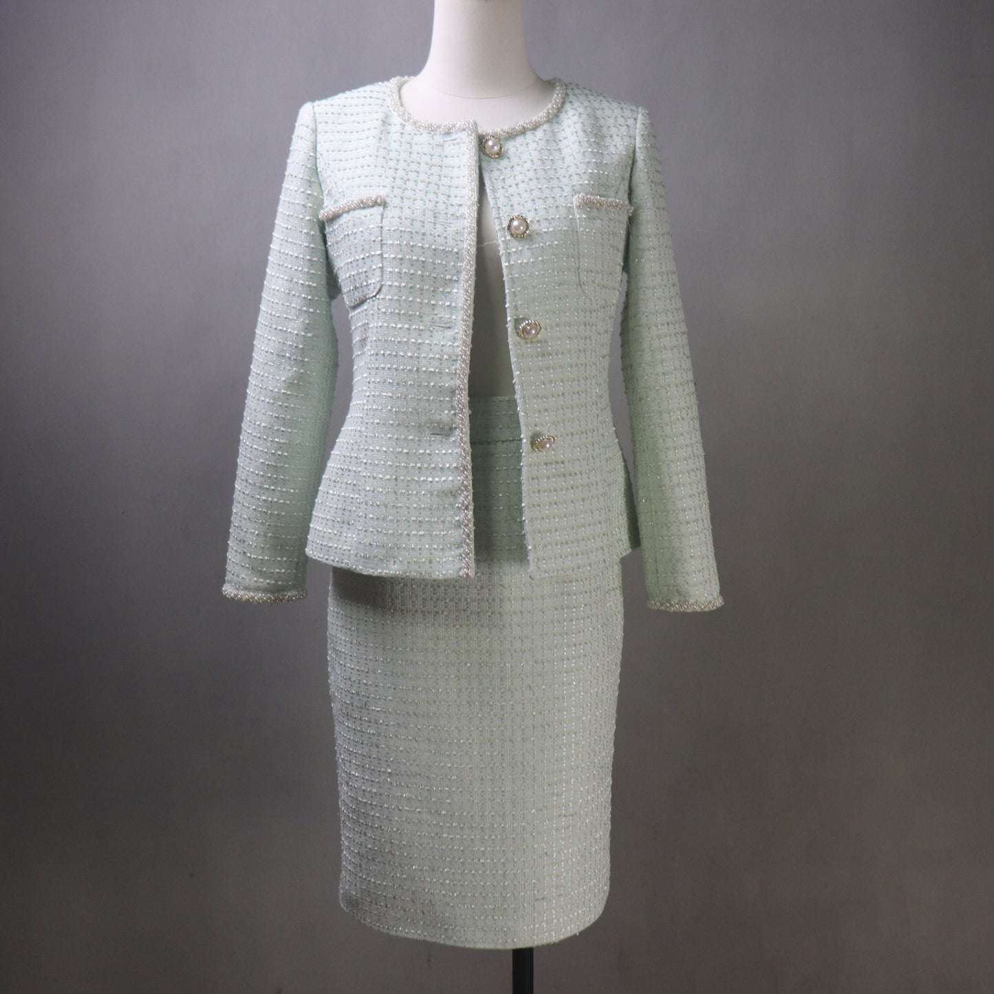 Light green tweed suit on a mannequin against a gray background