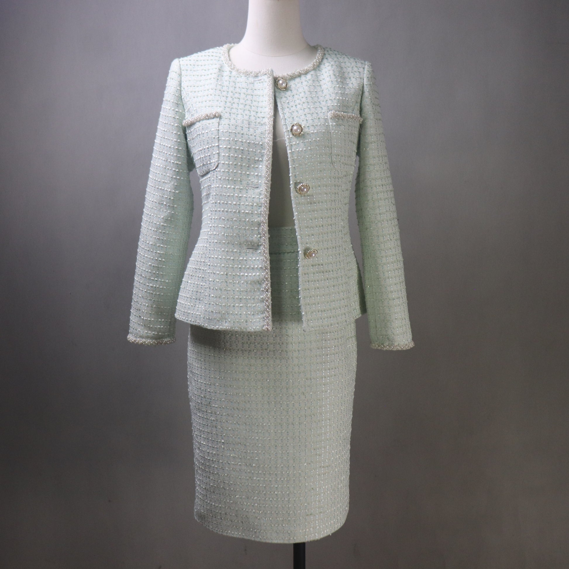 Light green tweed suit on a mannequin against a gray background