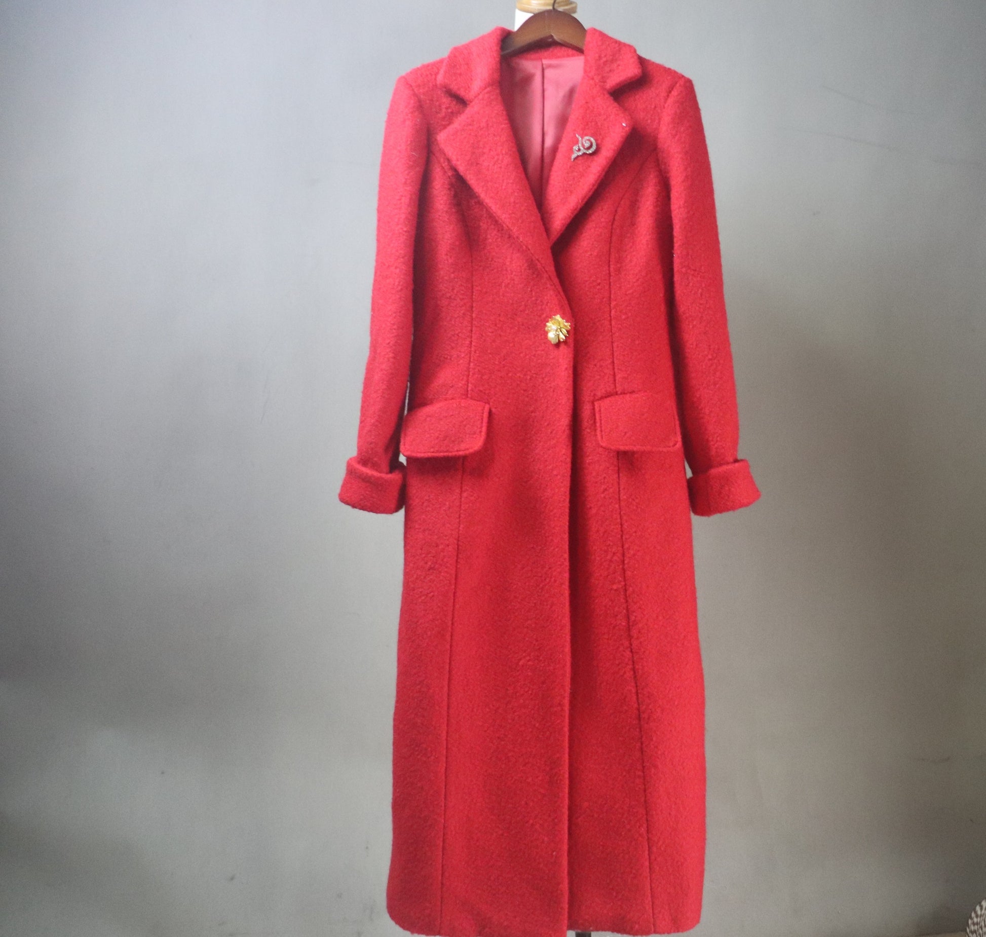 High-quality, custom-made, tailored long red wool winter coat, designed for a perfect fit and luxurious warmth. This bespoke piece features a classic single-breasted silhouette, wide notched lapels, and high-quality fabrication, styled here for a festive European winter look. The coat's striking color and precise construction emphasize the artistry of custom garment creation, ideal for clients seeking personalized, high-fashion cold-weather outerwear and unique apparel.