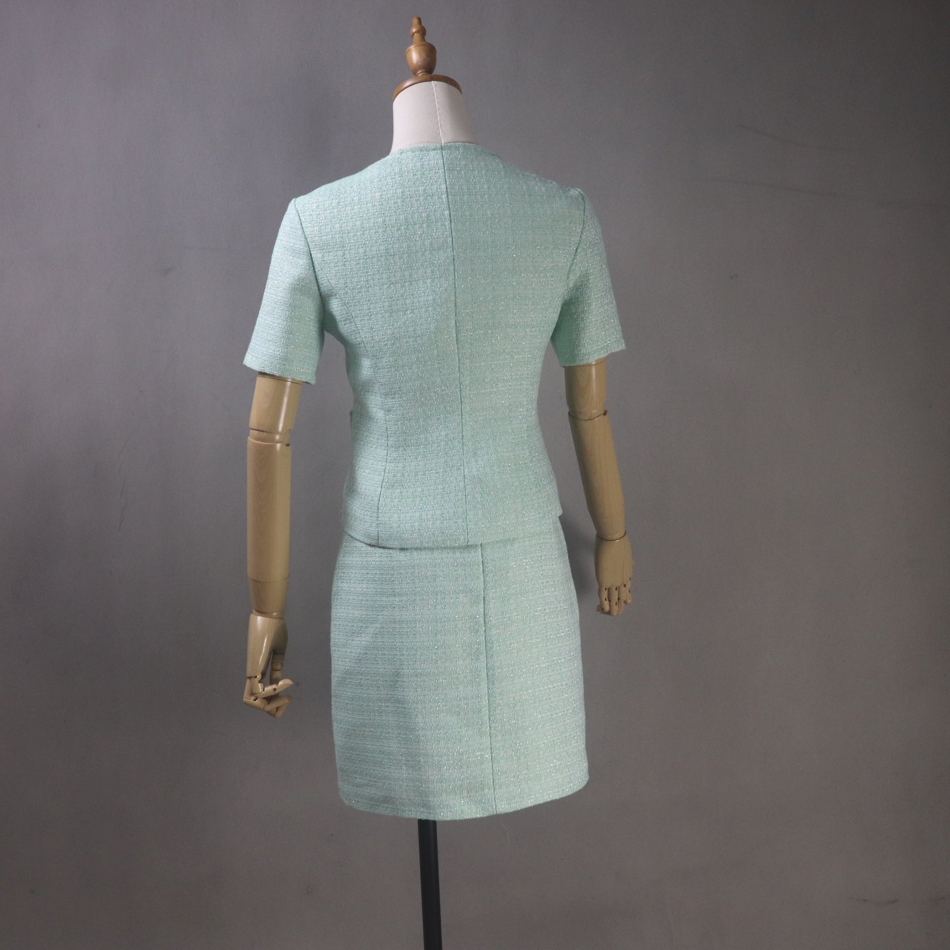 Green suit on a mannequin against a gray background