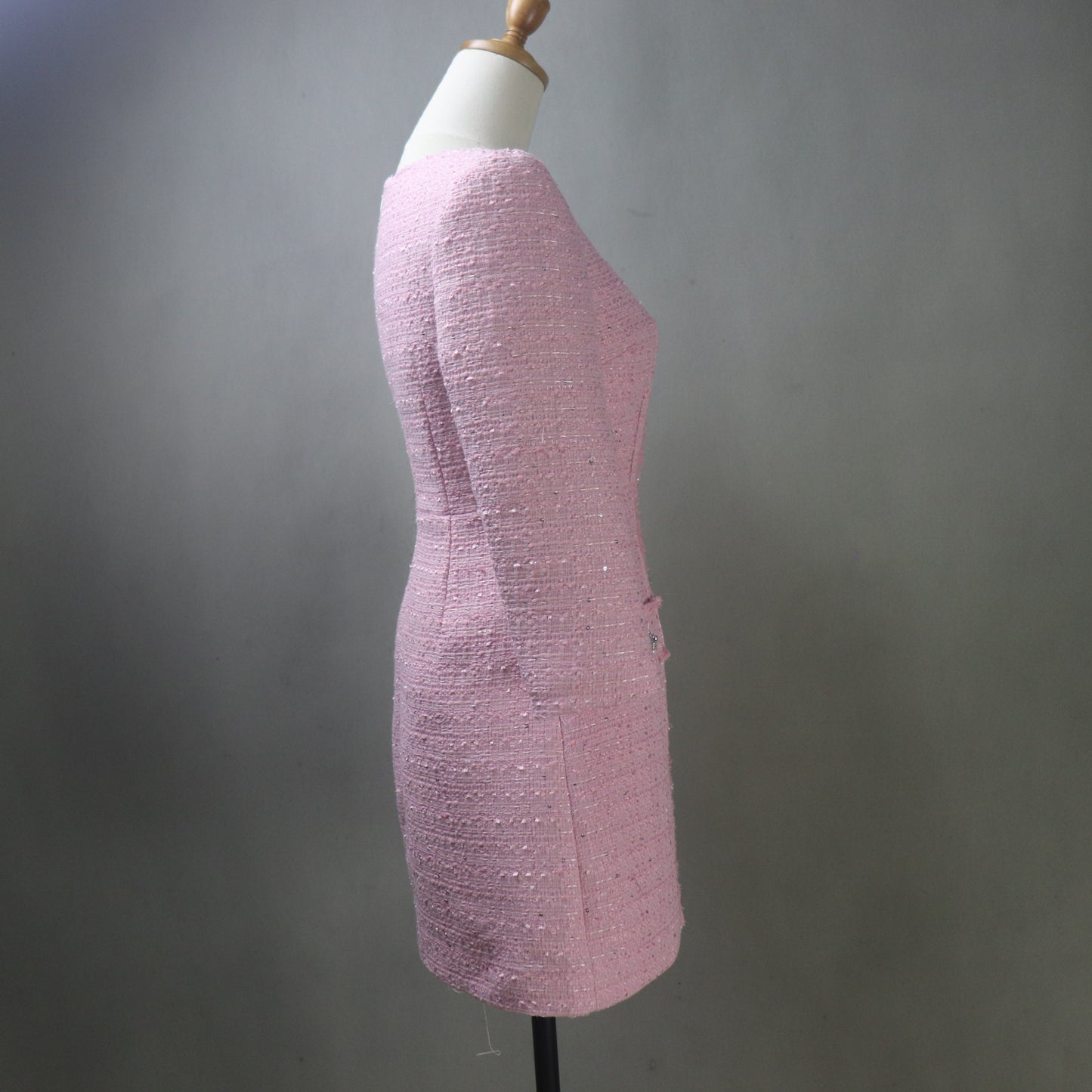 Pink textured dress on a mannequin against a gray background