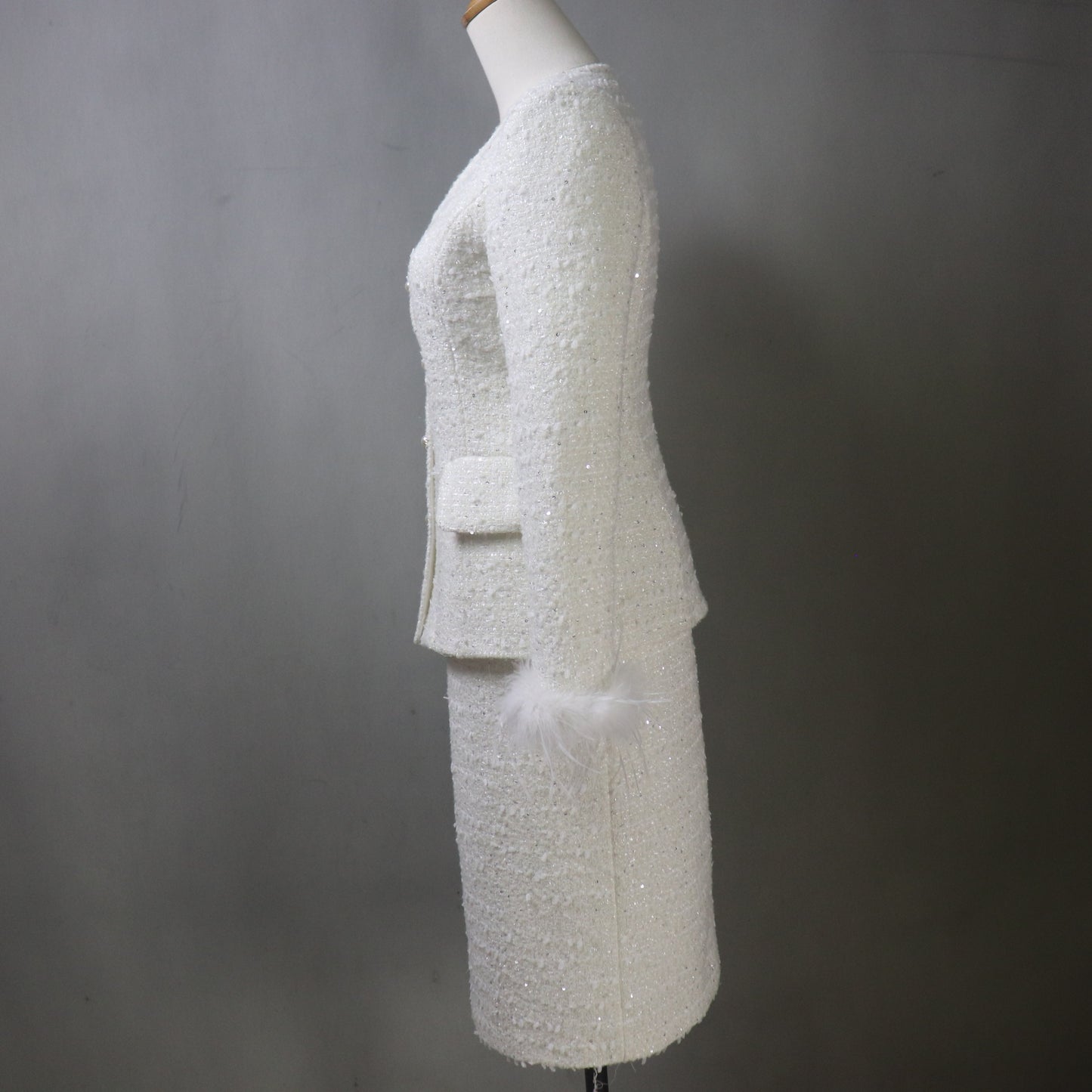 White textured suit on a mannequin against a gray background