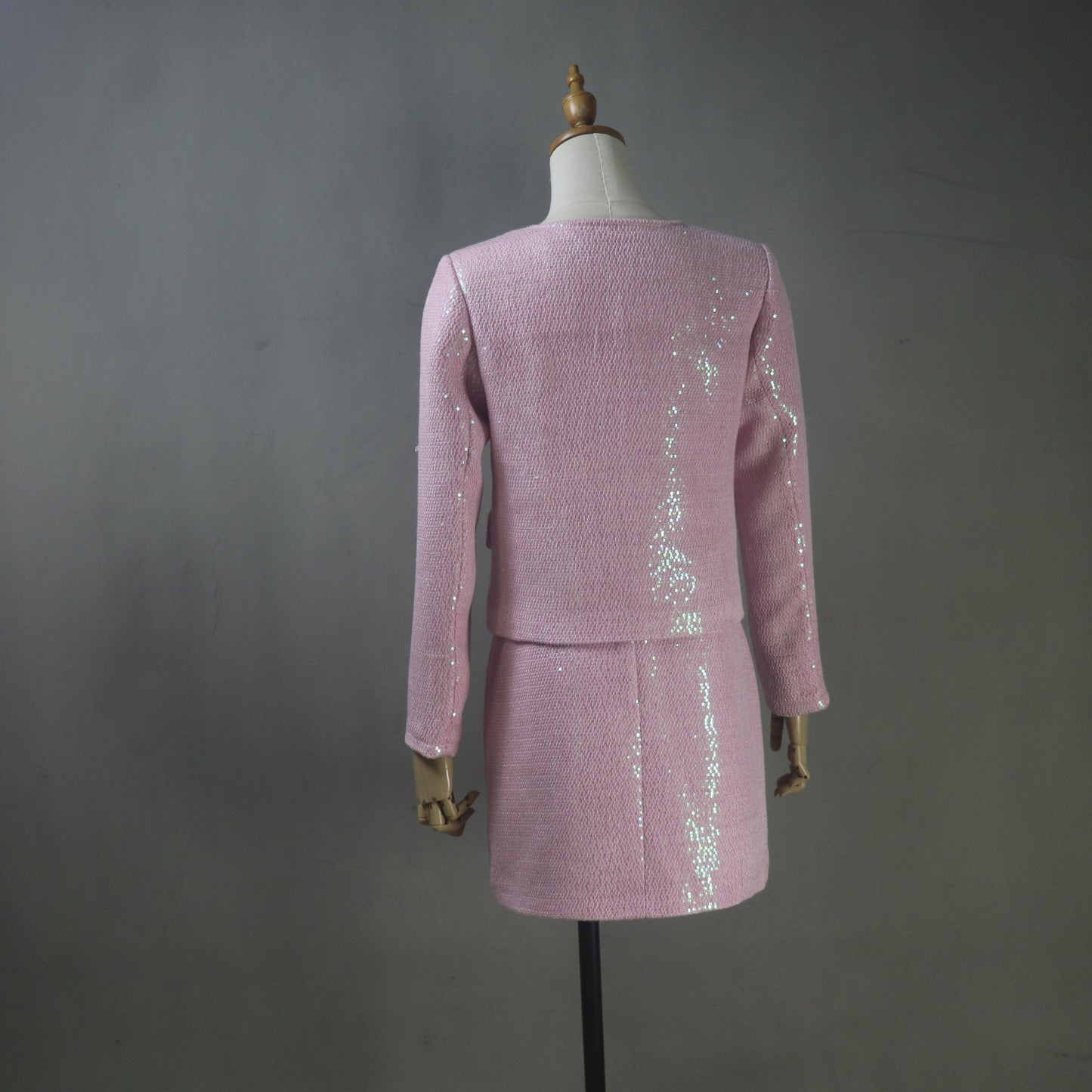 Pink sequined outfit on a mannequin against a gray background