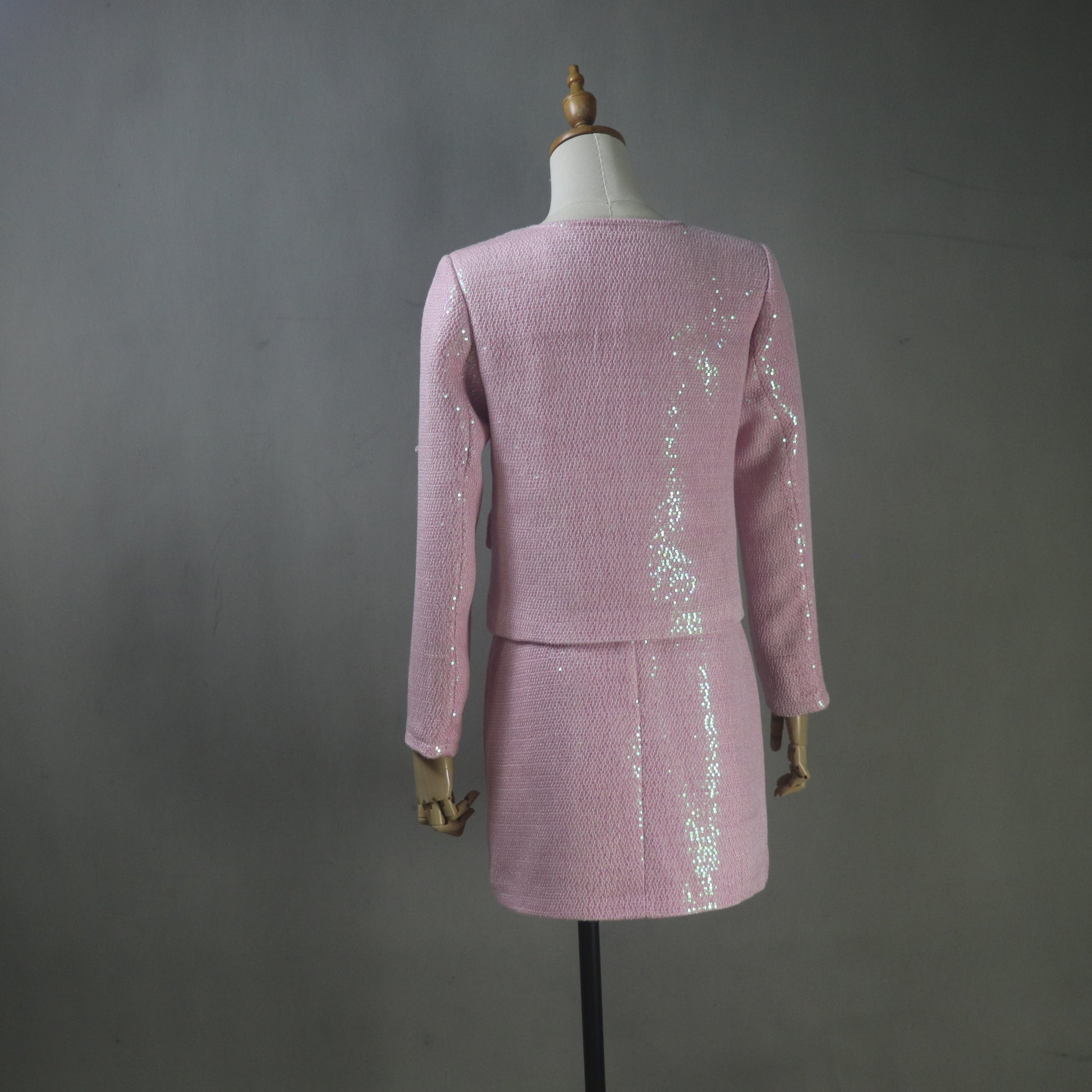Pink sequined outfit on a mannequin against a gray background