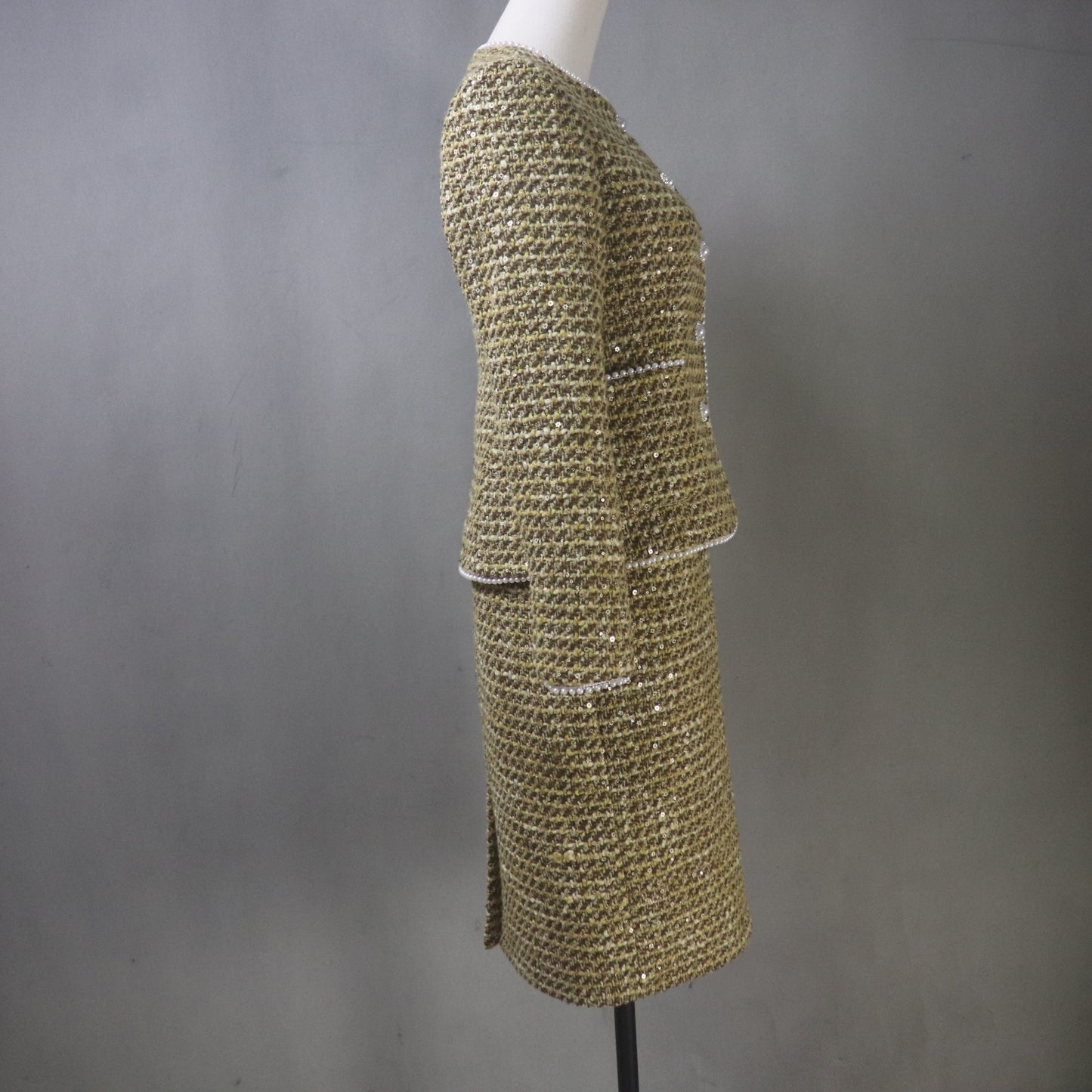 Gold textured coat on a mannequin against a gray background