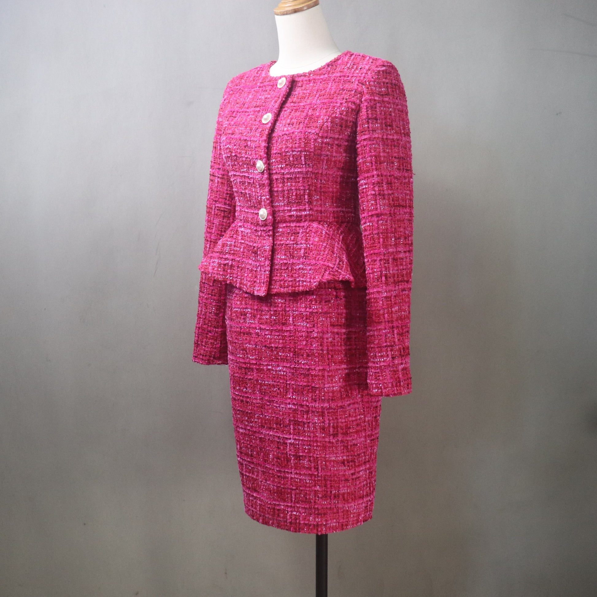 Pink tweed suit on a mannequin against a gray background