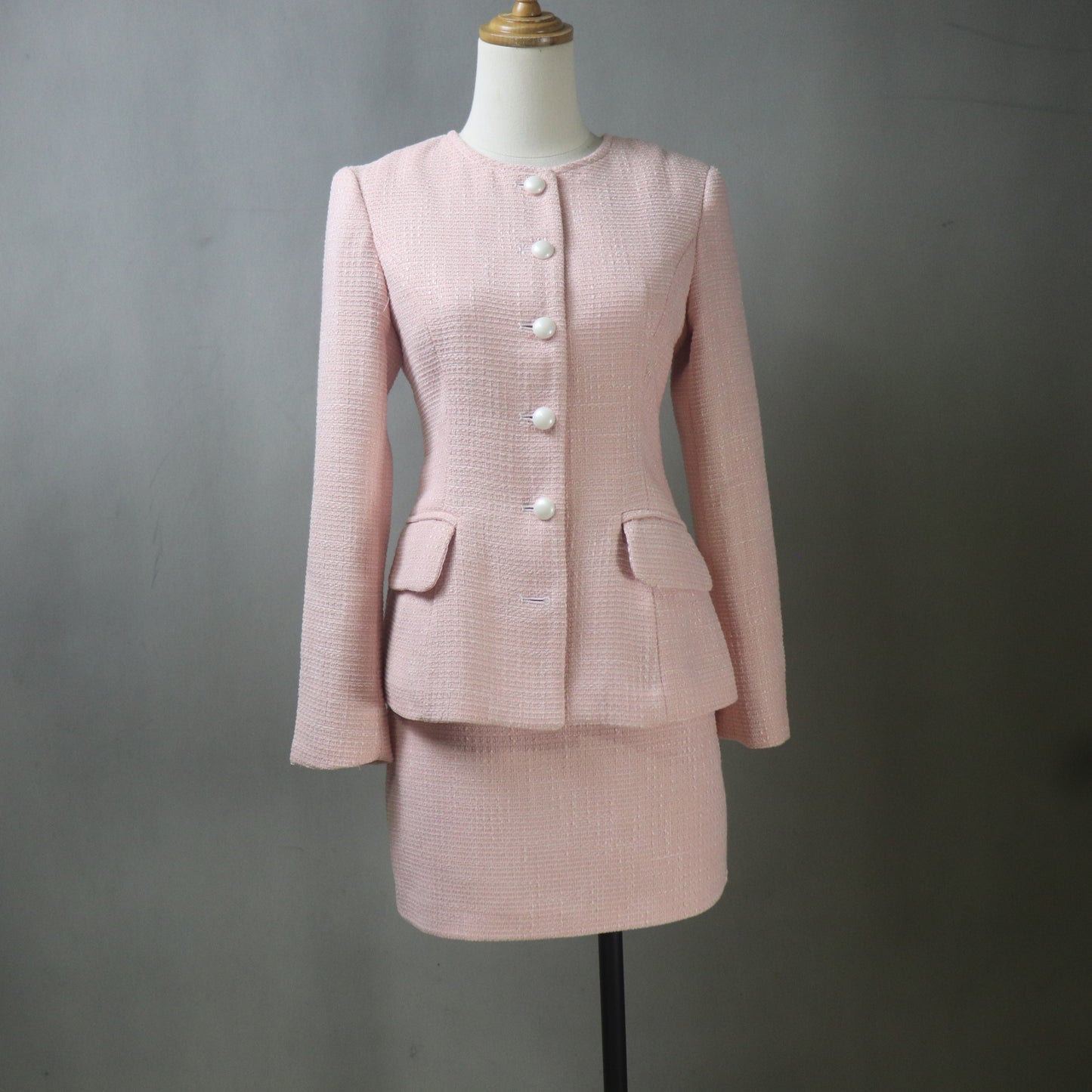 Pink suit on a mannequin against a gray background