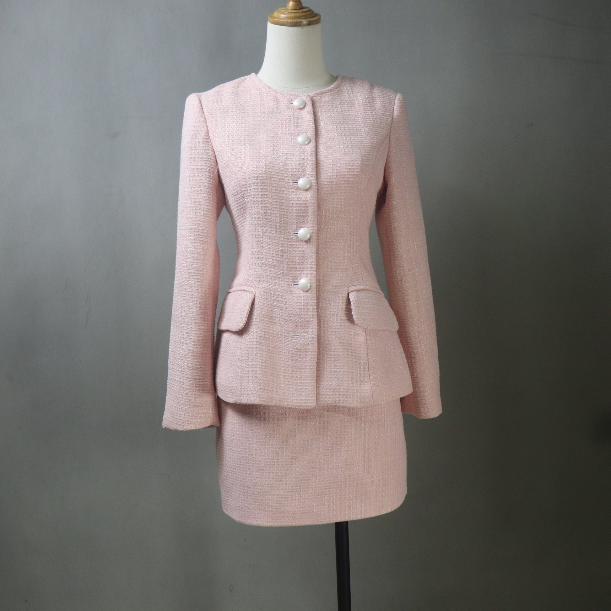 Pink suit on a mannequin against a gray background