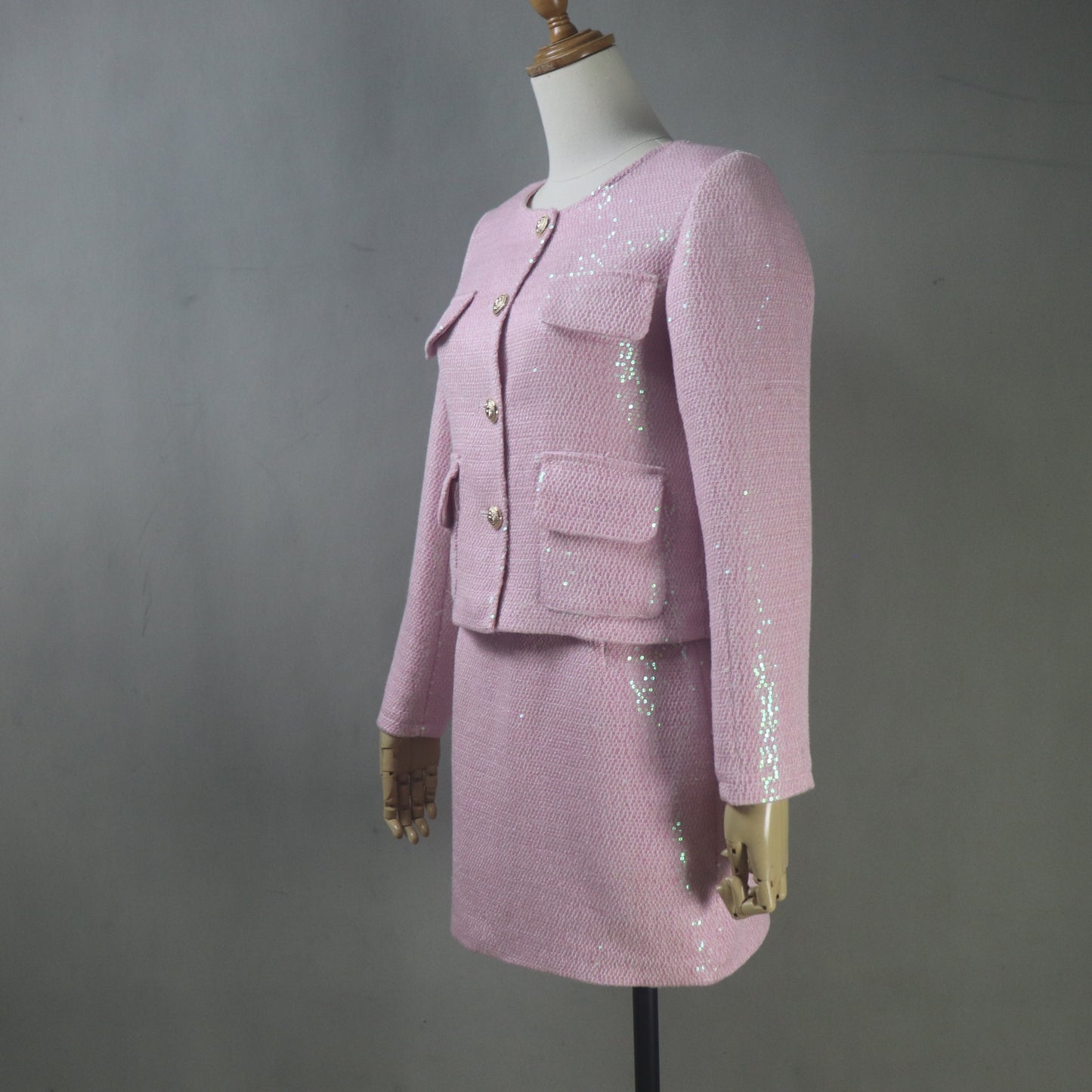 Pink sequined suit on a mannequin against a gray background