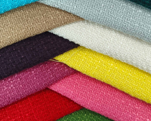 Stack of colorful fabric swatches in various textures and colors.