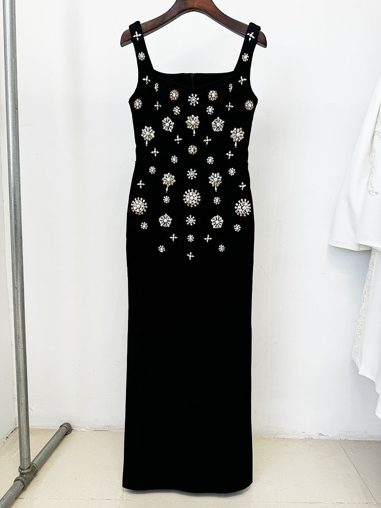 Black dress with white floral embellishments on a hanger against a white background