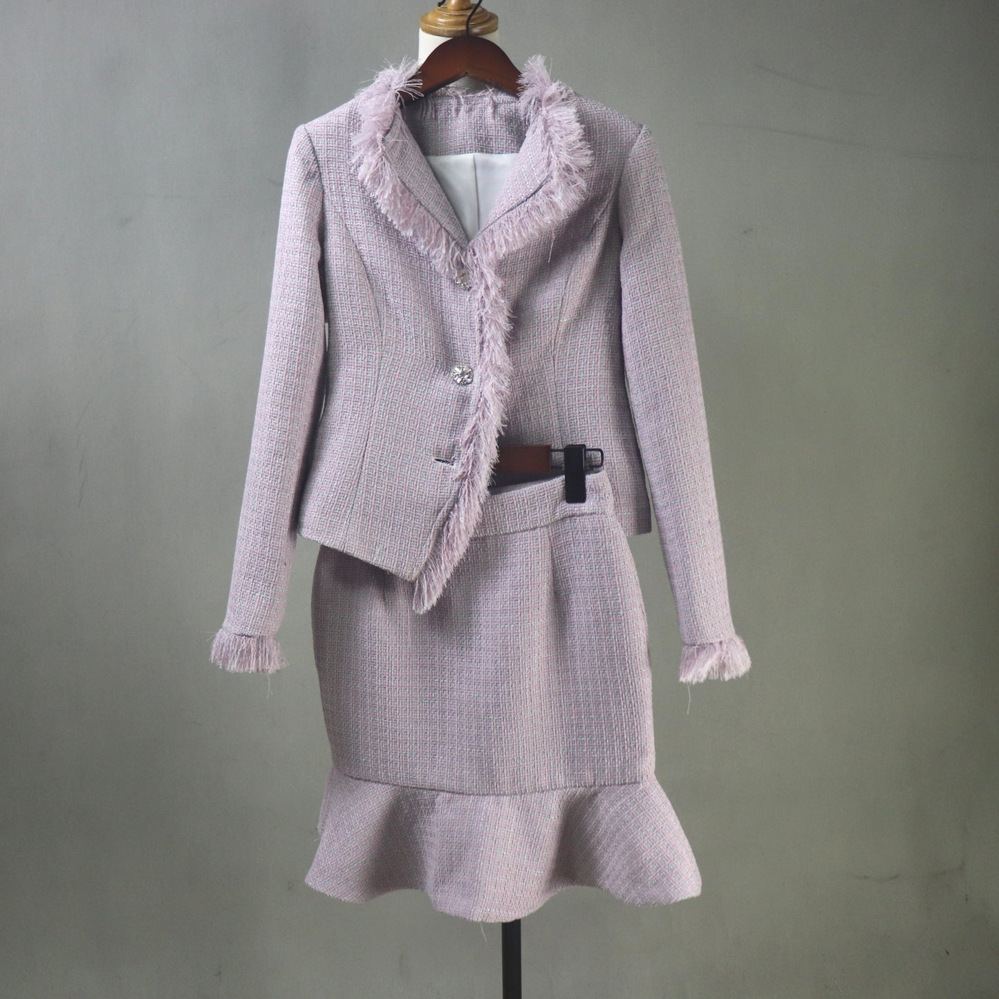 Purple suit with frayed edges on a mannequin against a gray background
