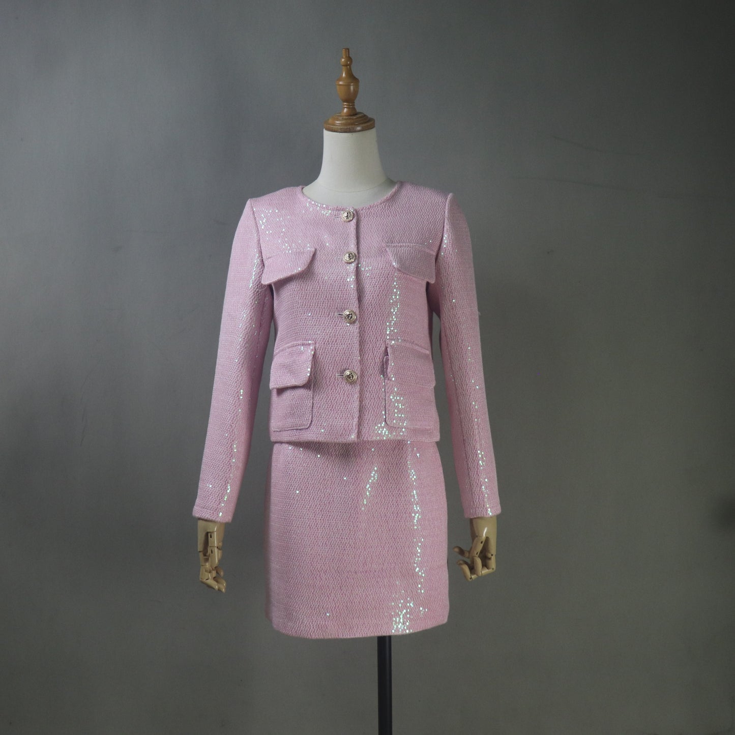 Pink sequin suit on a mannequin against a gray background