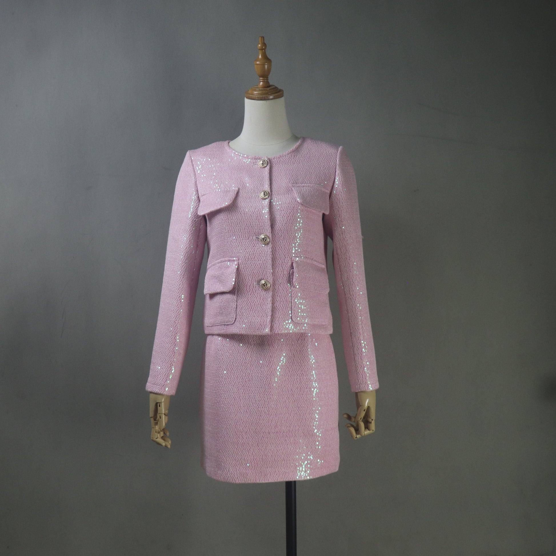 Pink sequin suit on a mannequin against a gray background