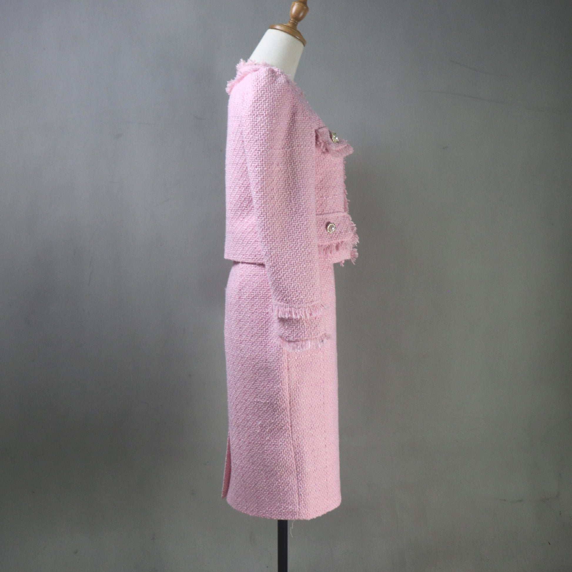 Pink textured suit on a mannequin against a gray background