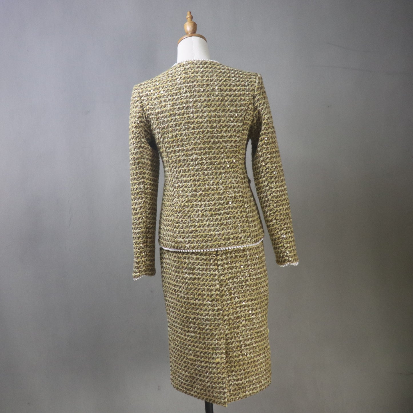 Gold textured dress on a mannequin against a gray background