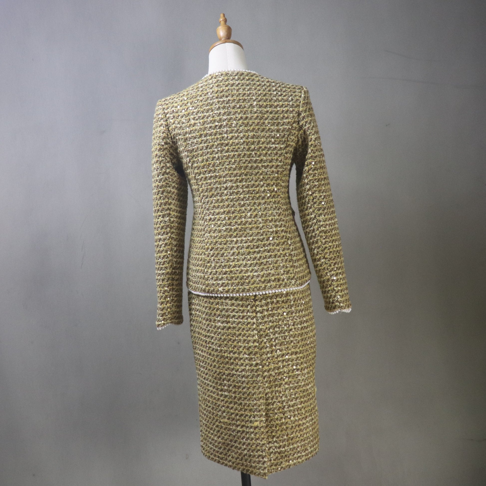 Gold textured dress on a mannequin against a gray background