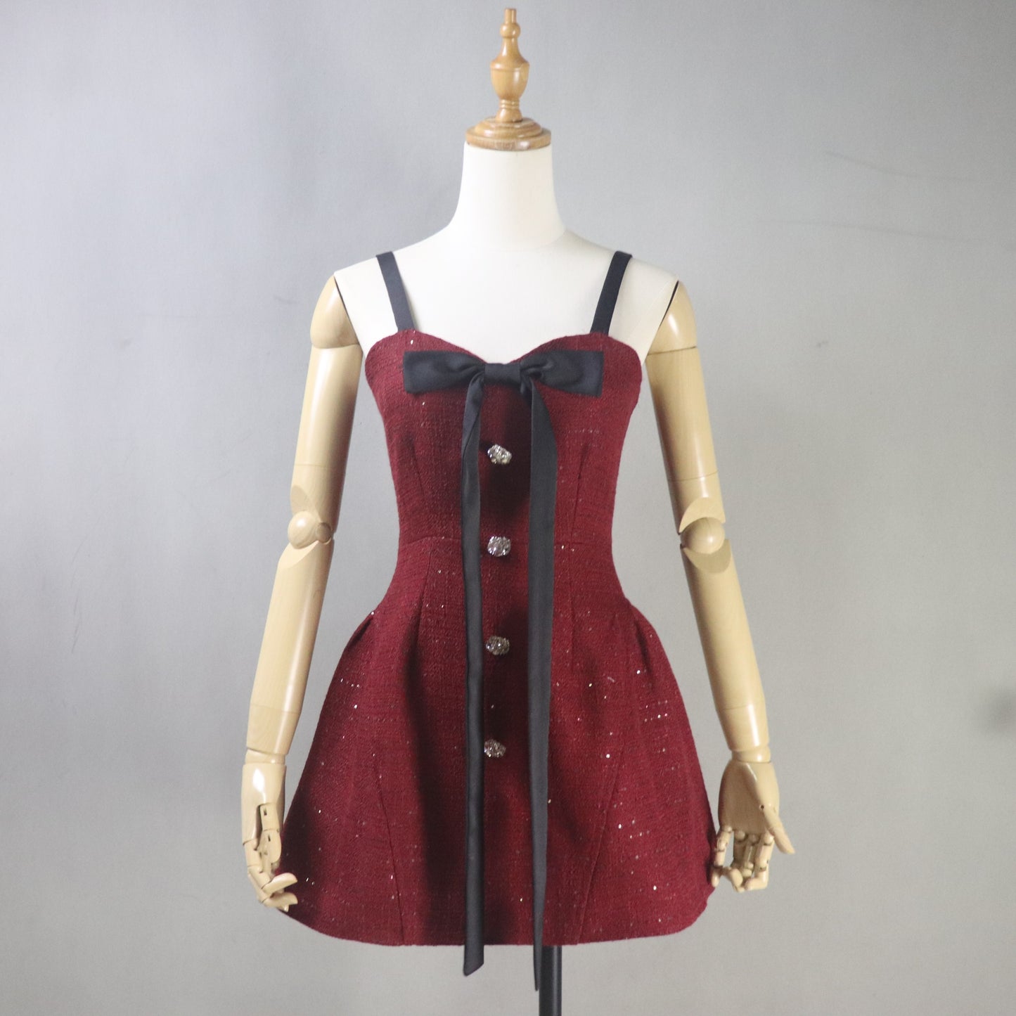 Red dress with black ribbon on a mannequin against a gray background