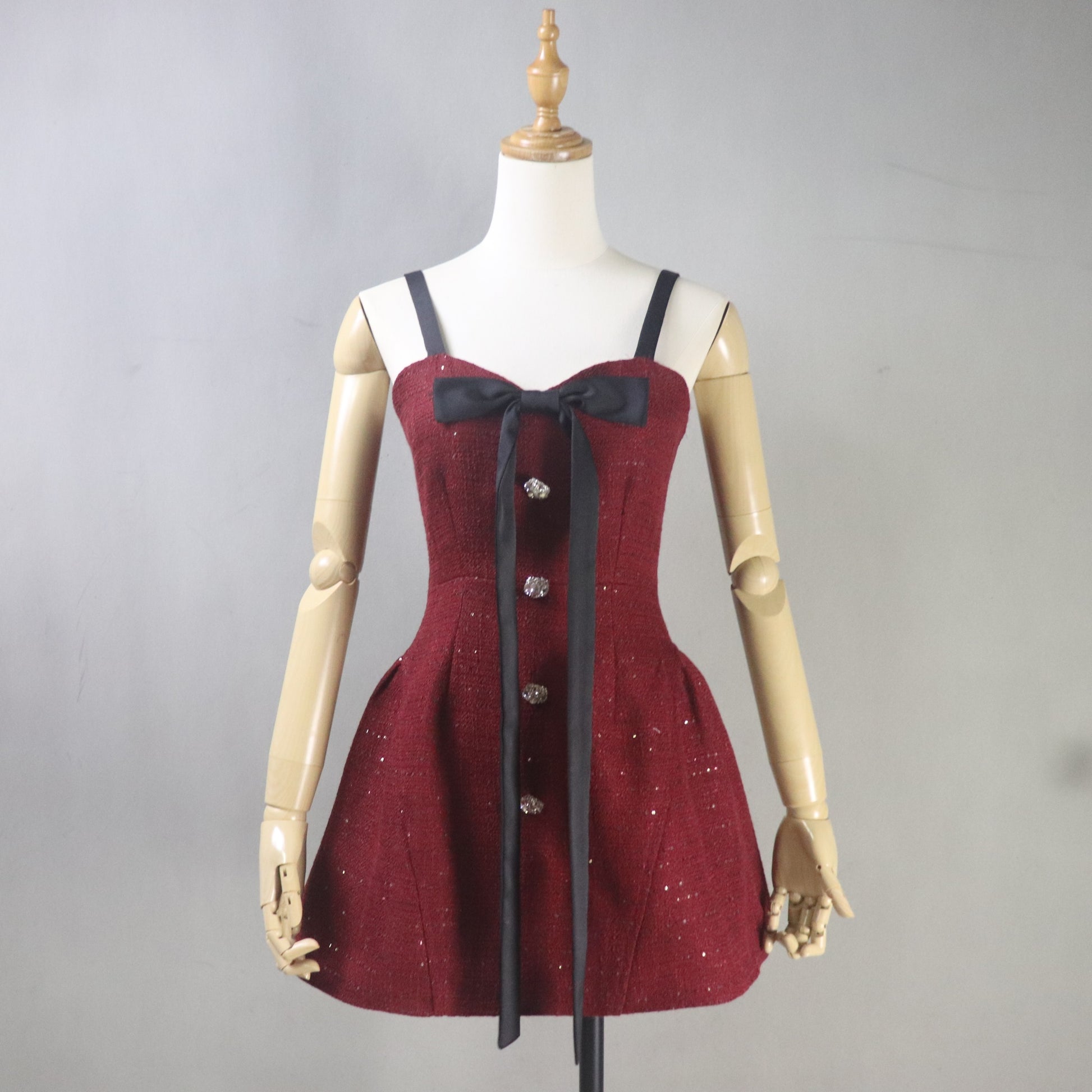 Red dress with black ribbon on a mannequin against a gray background