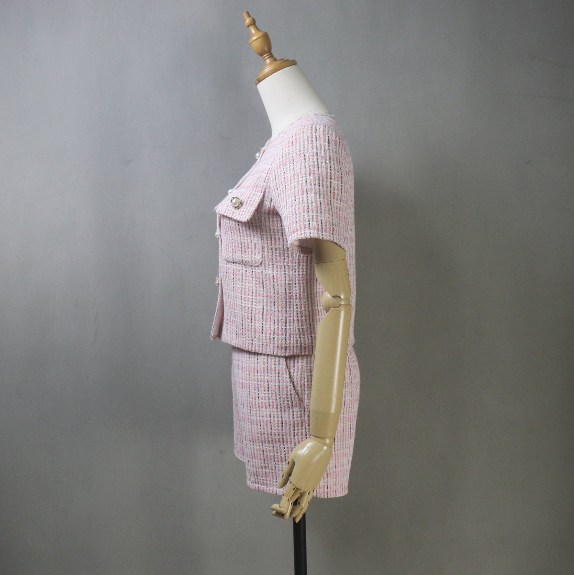 Side view of mannequin in pink tweed summer suit, showcasing the short-sleeved blazer’s tailored fit and the high-waisted shorts’ flattering silhouette