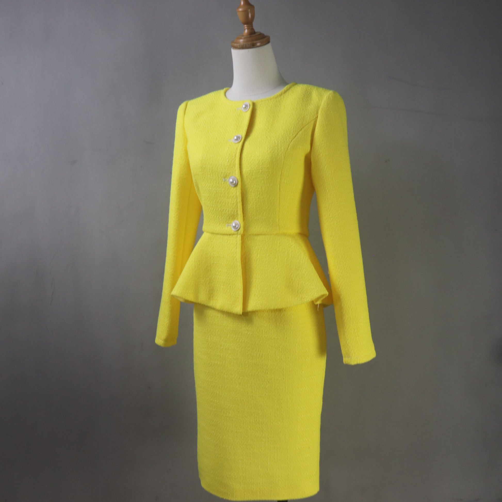 Woman wearing bright yellow tailored skirt suit with peplum jacket and knee-length pencil skirt, sophisticated special occasion outfit