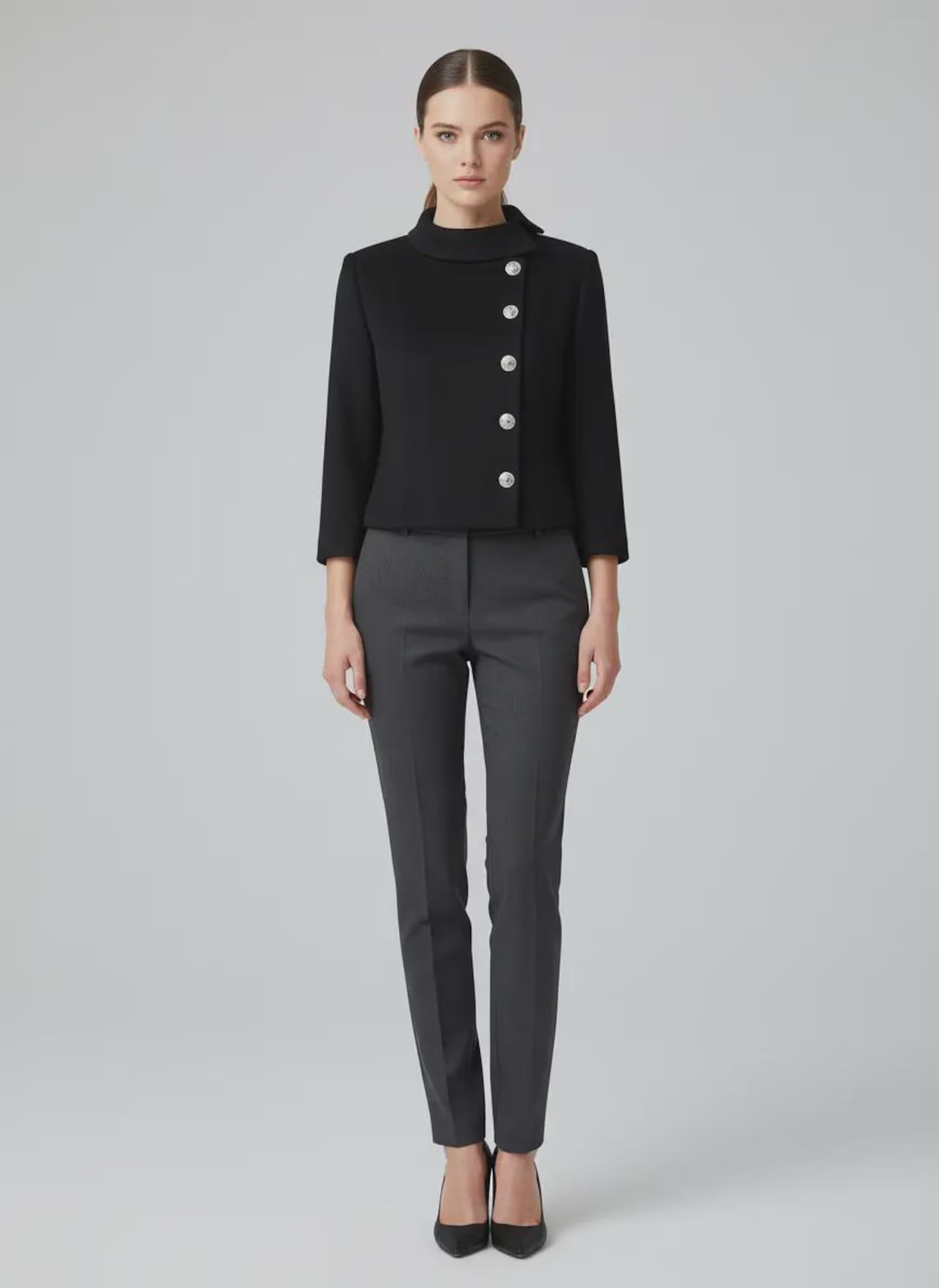 Close-up of a custom-made black cropped wool jacket for women, featuring a structured Nehru collar and five ornate silver buttons in a side-closure military style on a mannequin.