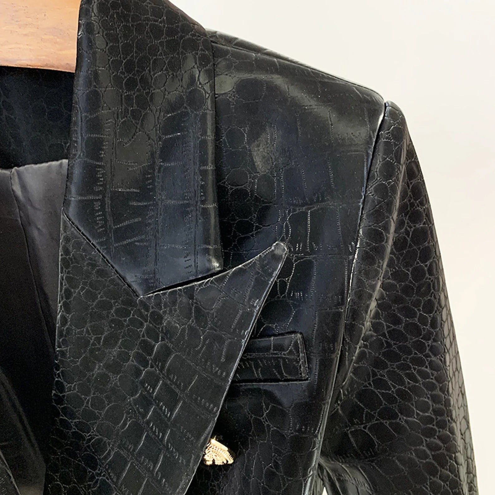 This faux crocodile leather blazer is a must-have for the next Autumn/Winter season. The leather texture adds a touch of refinement to any outfit. The jacket appears to be luxurious and classic due to its crocodile leather appearance. To finish the outfit, pair it with a basic white bodysuit, light wash denim, and chunky sneakers in a black fake leather croc-effect material with a button up front and fit.